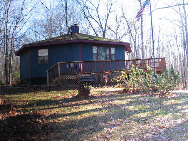 back of property with a yard and a wooden deck