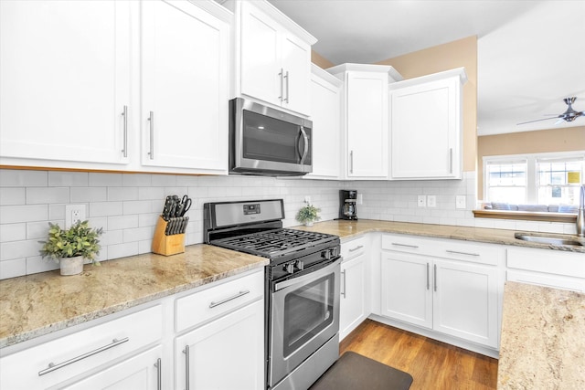 kitchen featuring stainless steel appliances, backsplash, sink, white cabinets, and light hardwood / wood-style flooring