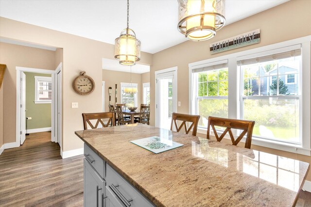 kitchen featuring a wealth of natural light, dark hardwood / wood-style floors, pendant lighting, and light stone counters