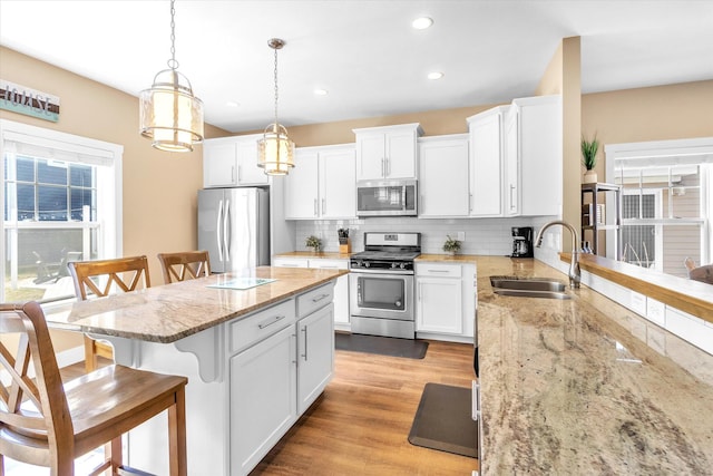 kitchen with pendant lighting, stainless steel appliances, sink, and white cabinets