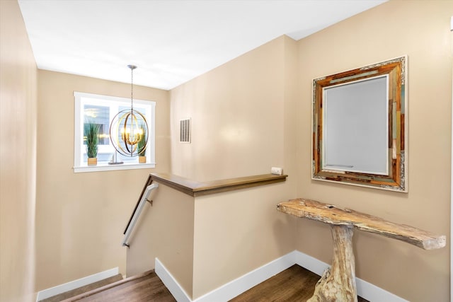 stairway with a chandelier and hardwood / wood-style flooring