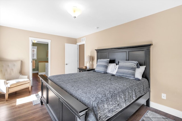 bedroom featuring ensuite bathroom and dark hardwood / wood-style floors