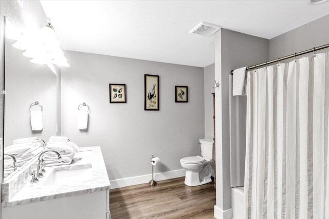 full bathroom with hardwood / wood-style floors, shower / tub combo with curtain, vanity, and toilet