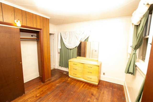 bedroom featuring dark hardwood / wood-style flooring, ornamental molding, and a closet