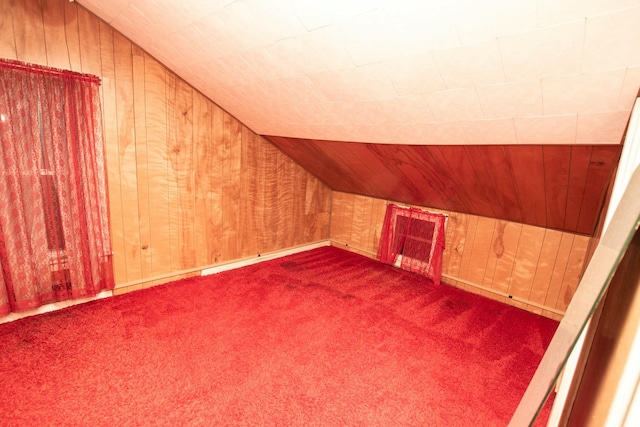 additional living space featuring wood walls, carpet floors, and vaulted ceiling