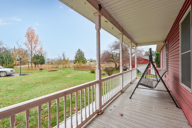 wooden terrace featuring a porch and a lawn