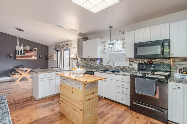 kitchen with black appliances, a kitchen island, sink, and pendant lighting