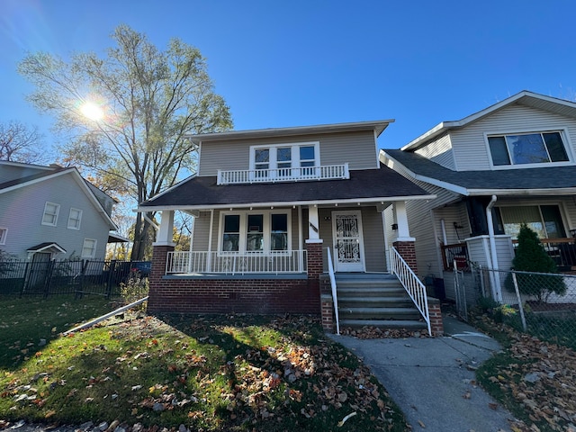 view of front facade featuring a balcony, covered porch, and a front yard