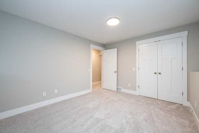 unfurnished bedroom with light carpet and a closet