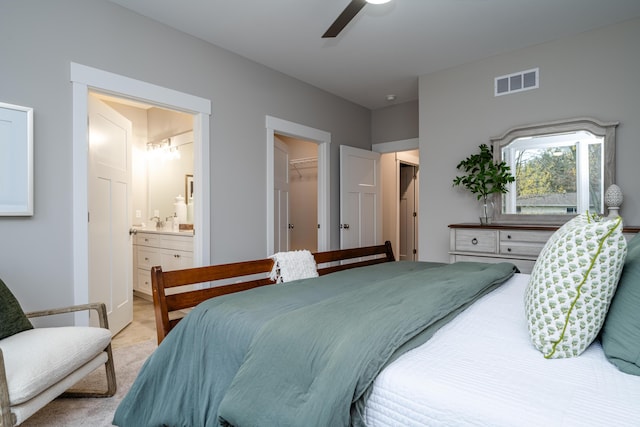 carpeted bedroom featuring ensuite bathroom, ceiling fan, a walk in closet, and a closet