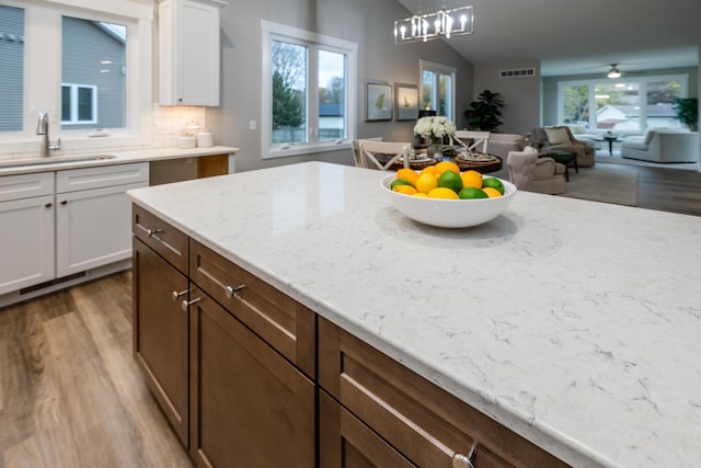 kitchen with hardwood / wood-style floors, white cabinetry, sink, and pendant lighting