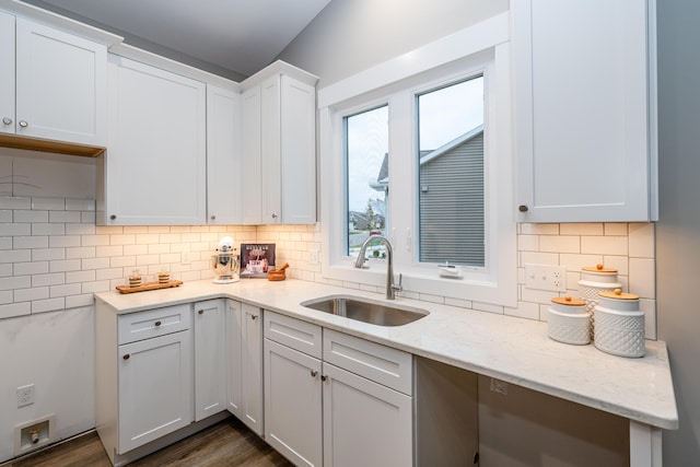 kitchen with white cabinets, sink, light stone countertops, tasteful backsplash, and dark hardwood / wood-style flooring