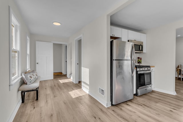 kitchen with light wood-type flooring, white cabinetry, and appliances with stainless steel finishes