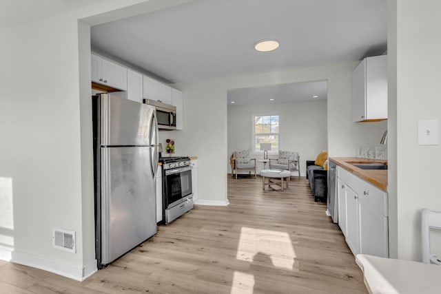 kitchen featuring white cabinets, appliances with stainless steel finishes, light hardwood / wood-style flooring, and sink