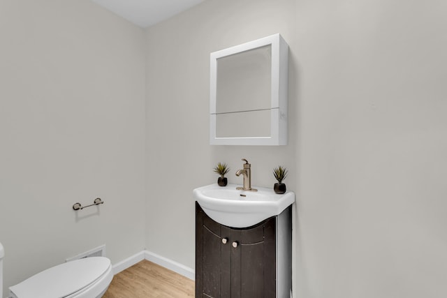 bathroom featuring vanity, hardwood / wood-style flooring, and toilet