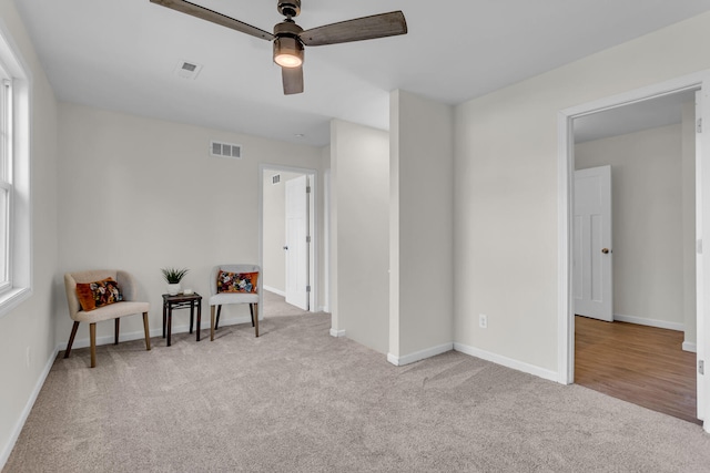 living area with ceiling fan and light colored carpet