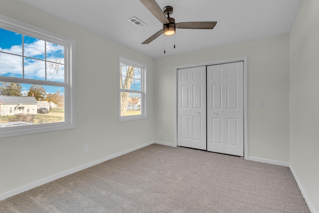 unfurnished bedroom featuring a closet, light colored carpet, and ceiling fan