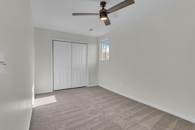 unfurnished bedroom with ceiling fan, light colored carpet, and a closet