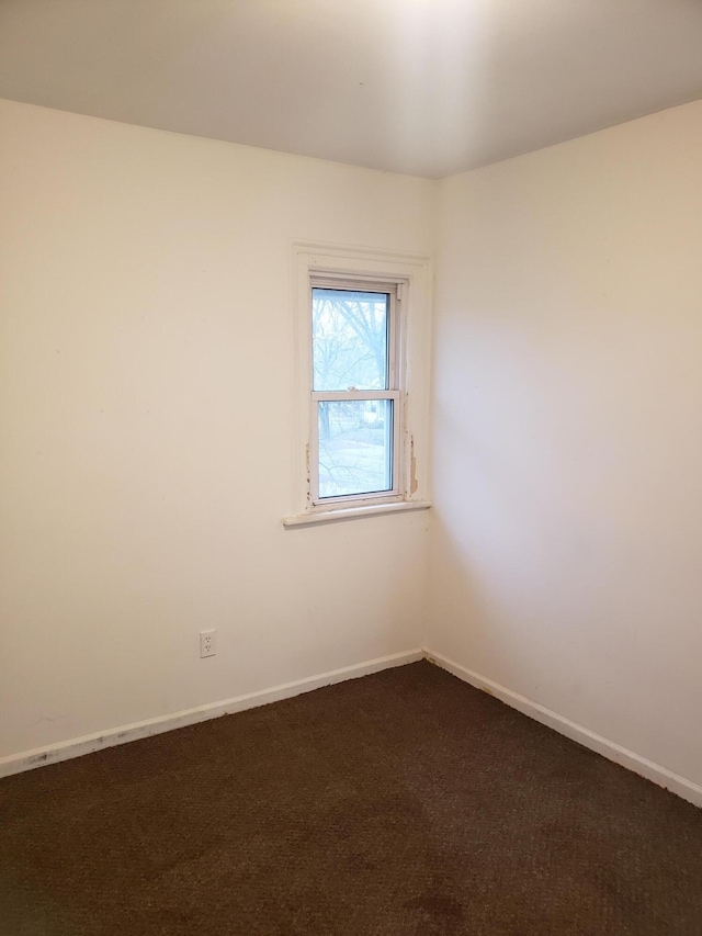 spare room with dark colored carpet