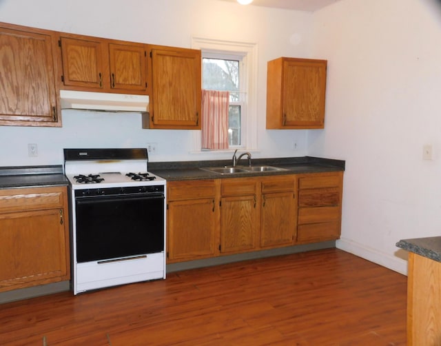 kitchen with white range with gas stovetop, dark wood-type flooring, and sink