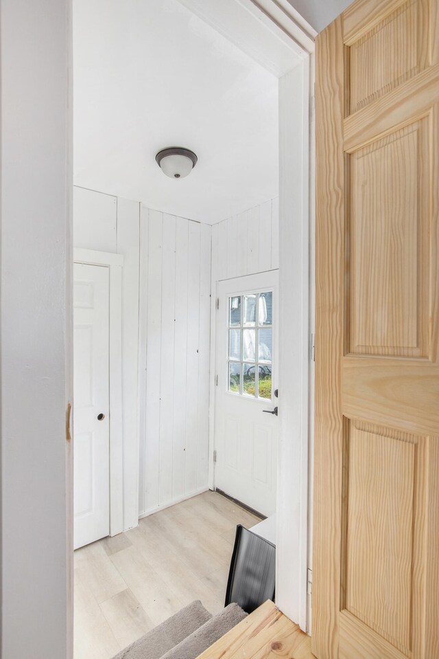 entryway featuring light wood-type flooring and wood walls