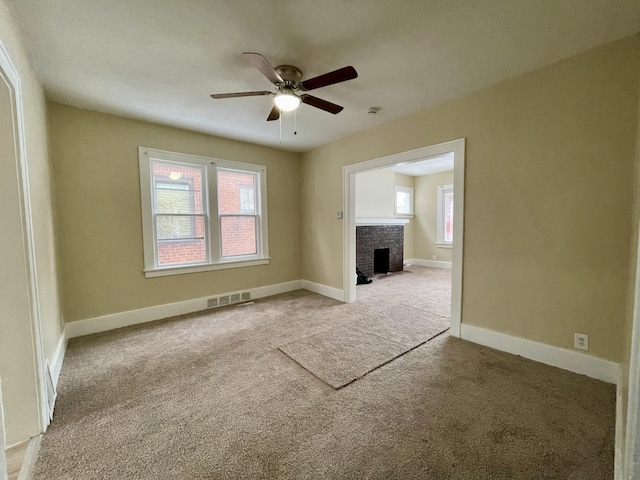 unfurnished living room with light carpet, a brick fireplace, and ceiling fan