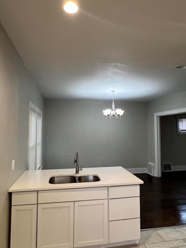 kitchen featuring sink, an inviting chandelier, decorative light fixtures, white cabinets, and light wood-type flooring