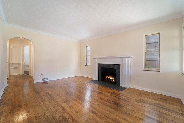 unfurnished living room with a textured ceiling, dark hardwood / wood-style floors, a brick fireplace, and ornamental molding