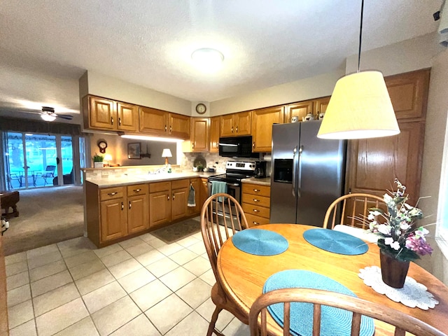 kitchen featuring ceiling fan, stainless steel appliances, pendant lighting, a textured ceiling, and light tile patterned floors