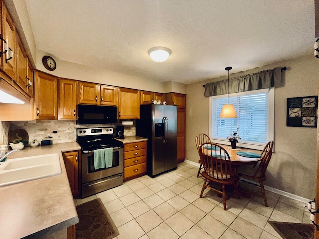 kitchen with sink, stainless steel appliances, a textured ceiling, decorative light fixtures, and light tile patterned flooring