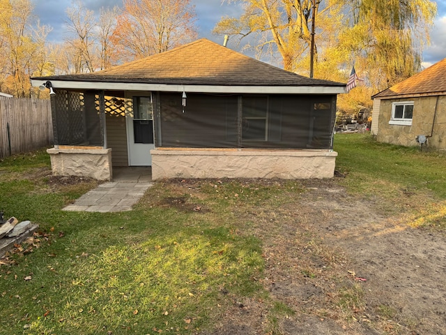 rear view of house featuring a lawn and a sunroom