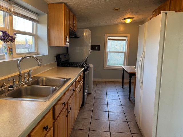 kitchen with stainless steel gas stove, white fridge with ice dispenser, plenty of natural light, and sink