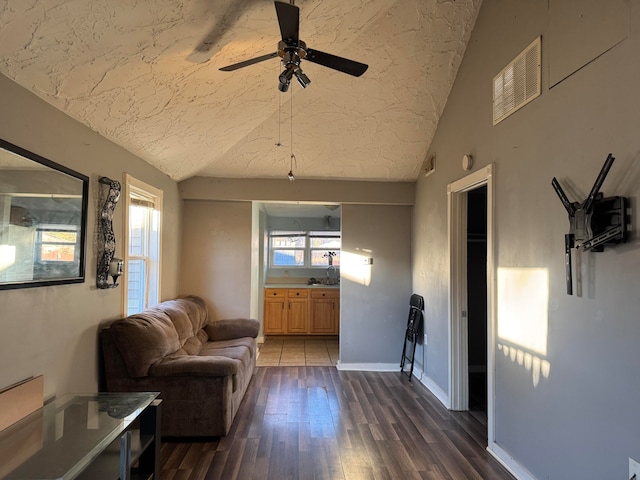 living room featuring a textured ceiling, lofted ceiling, ceiling fan, and dark wood-type flooring