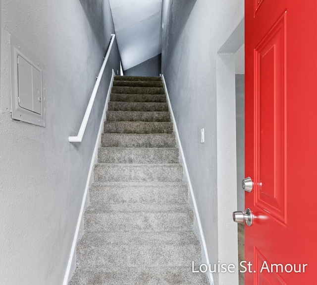 stairway featuring carpet, electric panel, and vaulted ceiling