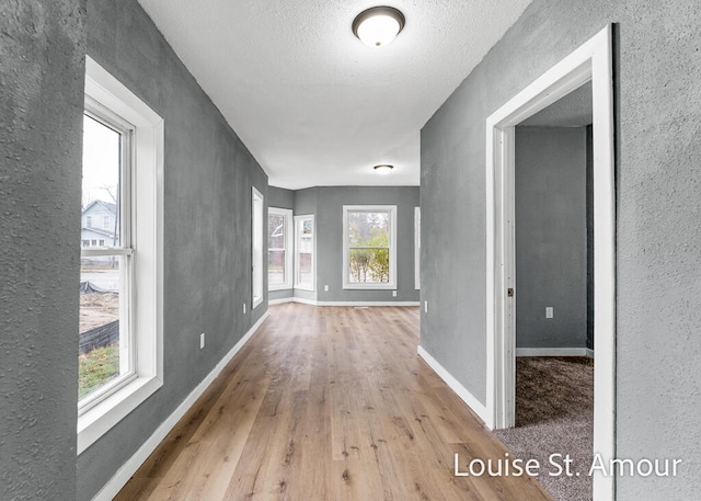 hall featuring light hardwood / wood-style flooring and a textured ceiling
