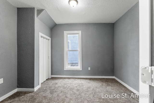 unfurnished bedroom featuring carpet flooring, a textured ceiling, and vaulted ceiling