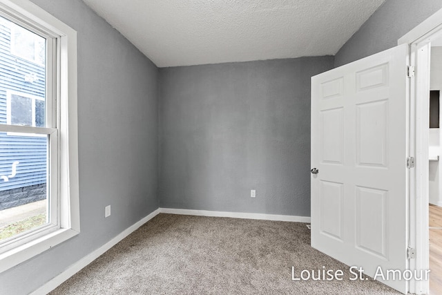 carpeted empty room featuring lofted ceiling and a textured ceiling