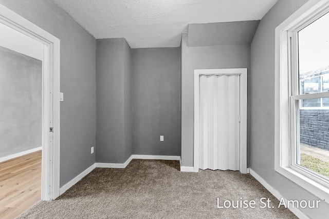 unfurnished bedroom featuring carpet, lofted ceiling, and a textured ceiling