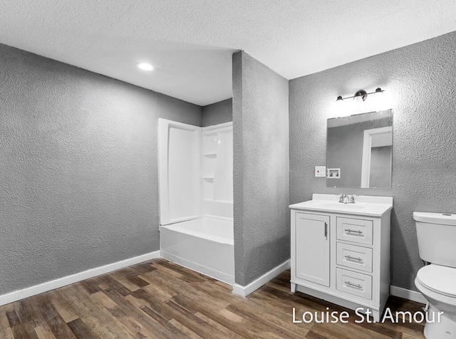 full bathroom with vanity, shower / tub combination, hardwood / wood-style flooring, toilet, and a textured ceiling