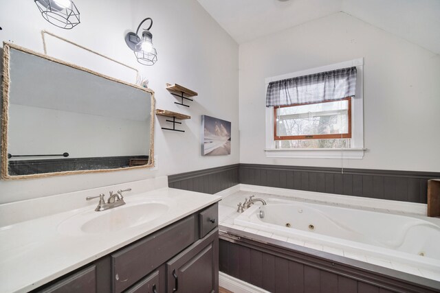 bathroom with vanity, a relaxing tiled tub, and lofted ceiling