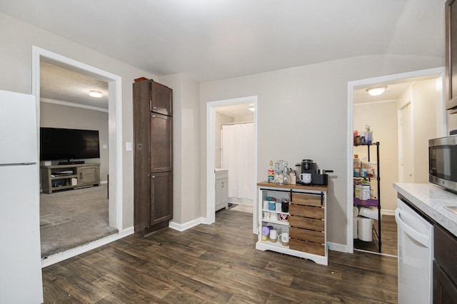 kitchen featuring dark brown cabinetry, crown molding, dark hardwood / wood-style flooring, and white appliances