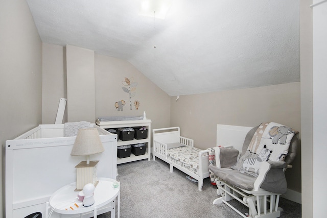 carpeted bedroom with a textured ceiling, a crib, and lofted ceiling