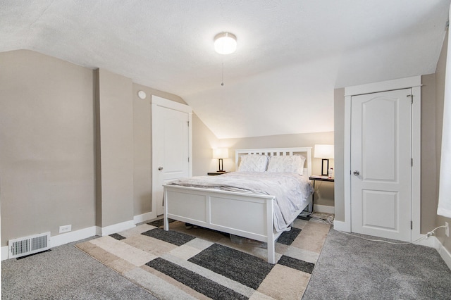 bedroom with dark colored carpet, a textured ceiling, and vaulted ceiling