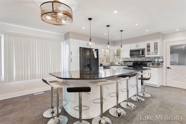 kitchen with black appliances, white cabinets, tasteful backsplash, decorative light fixtures, and a kitchen island