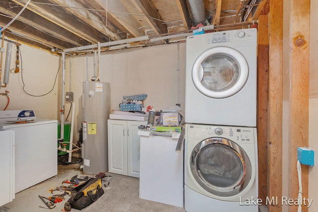 laundry area with cabinets, stacked washing maching and dryer, and water heater