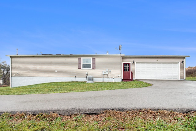 view of front of property with central air condition unit, a front lawn, and a garage