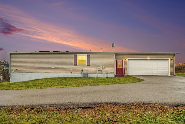 view of front of property featuring central AC unit, a garage, and a lawn