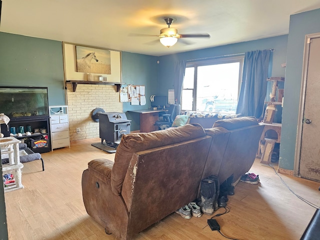 living room featuring ceiling fan, a wood stove, and light hardwood / wood-style flooring