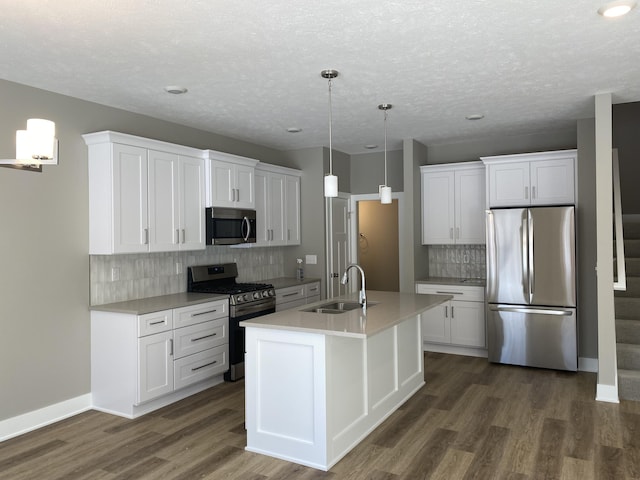 kitchen with sink, white cabinetry, hanging light fixtures, appliances with stainless steel finishes, and a kitchen island with sink