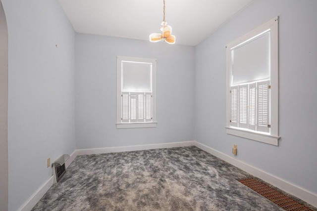 unfurnished room with plenty of natural light, carpet floors, and an inviting chandelier